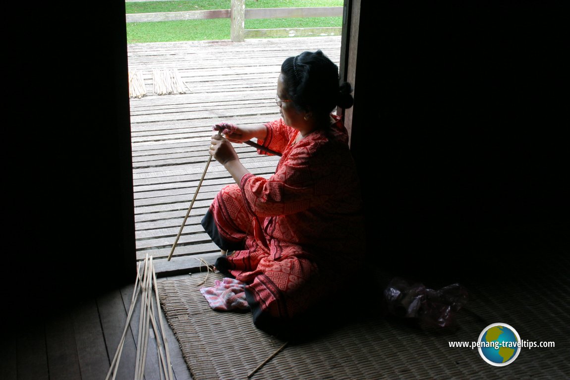 Iban woman splitting rattan at doorway of the longhouse