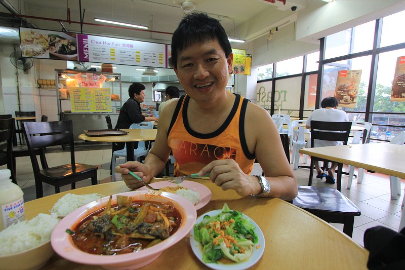 Tim trying the curry fish head at Sunshine Food Court