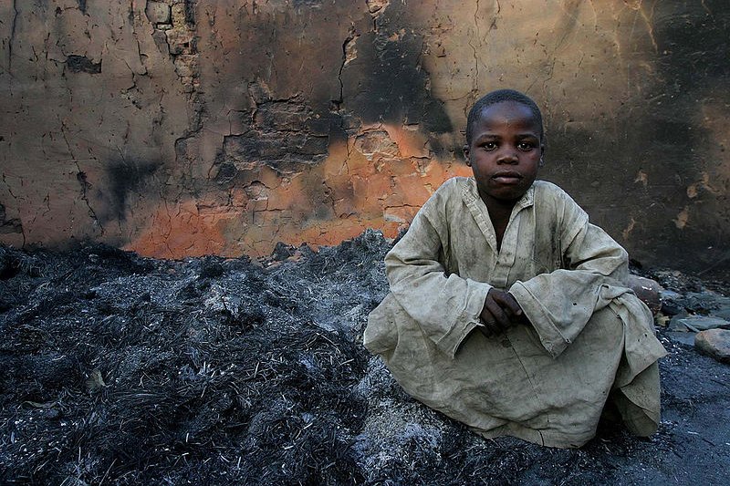 Boy with remains of house burnt in 2007 civil war, in Birao, CAR