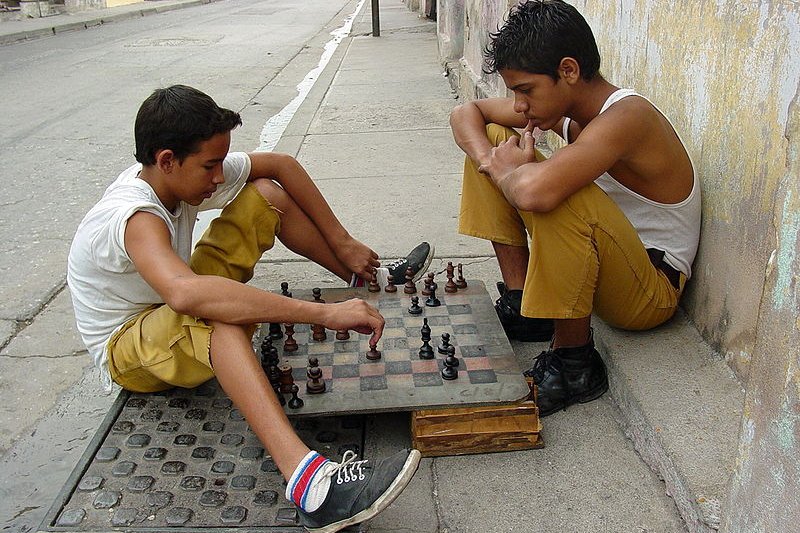 Boys playing chess on a sidewalk in Santiago de Cuba
