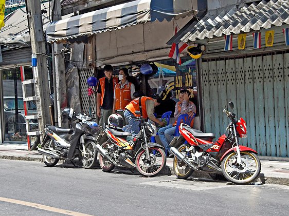 Motorcycle taxis waiting for customers along a Bangkok street
