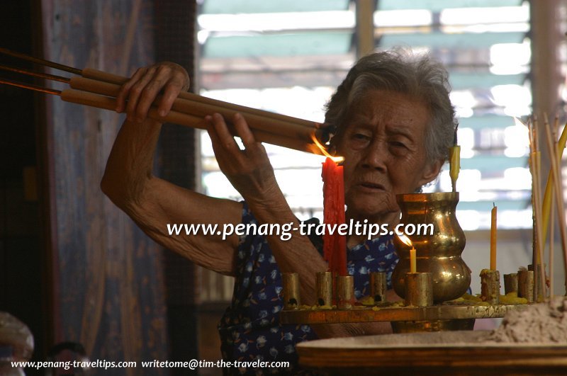 A devotee lighting joss sticks in Kuan Yin See